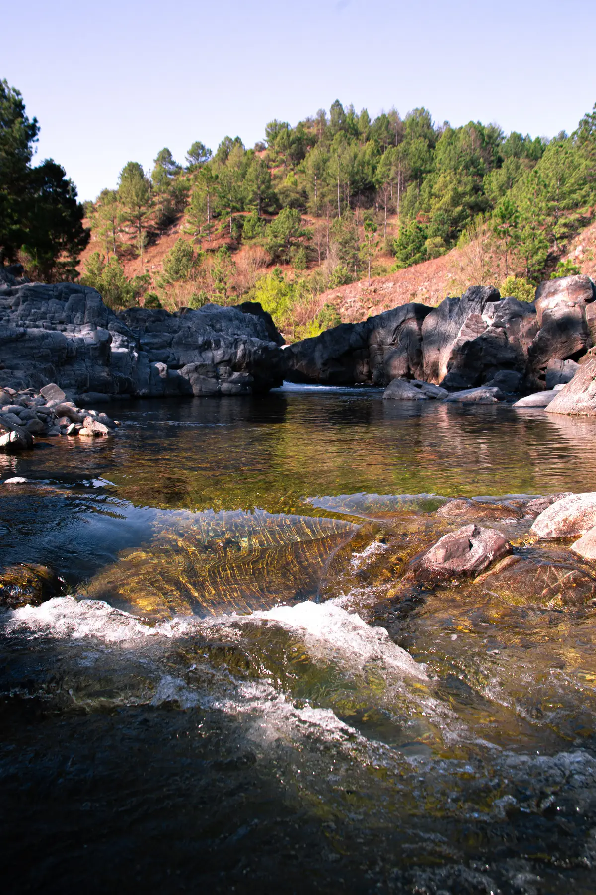 El río El Durazno entre rocas de granito y pinos, al pie de Cabañas Rundún